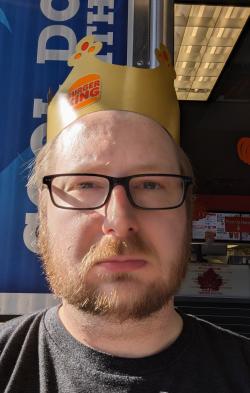 Don Riefler Headshot - Man with glasses, beard, and Burger King Crown on head