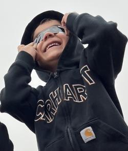 Young learner stands in black hoodie wearing a small with their safe solar viewing glasses.