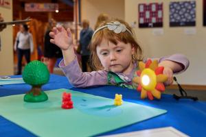 Young learner using a sun-shaped flashlight to make a shadow on small yellow and red toy bears