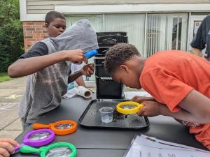Young participants investigate worms with magnifying glasses