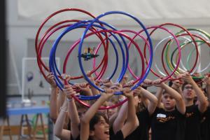 A Number of Students Stand Holding up HulaHoops as a Drone Flies through