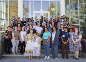 A large group of diverse individuals stands on a stair way forming multiple rows for a group photo.