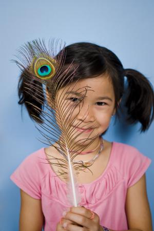 Girl looking at iridescent peacock feather with nanoscale color