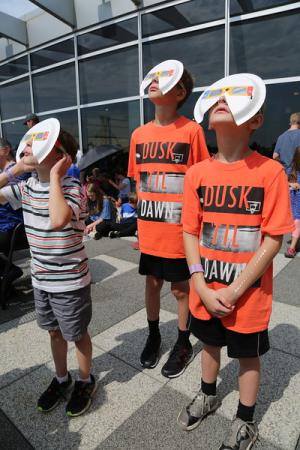 Children watching solar eclipse with safety viewers surrounded by paper plates