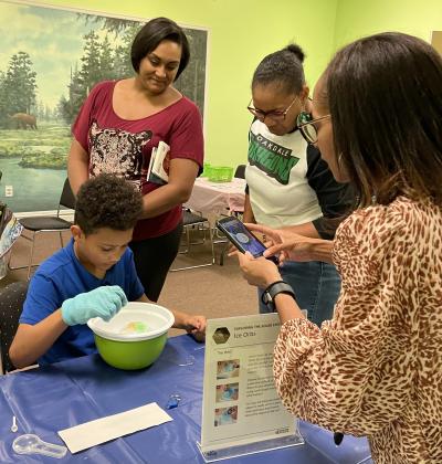 Audiences Crowd Around as a Student Engages with the Ice Orb Activity