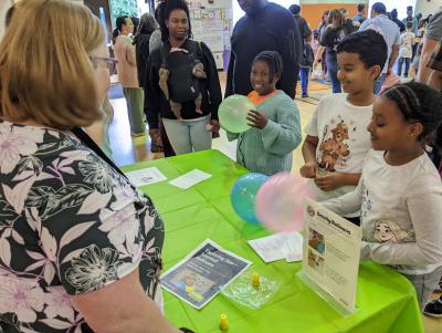 Greensboro Science Center family science night at Guilford Elementary School with children smelling balloons