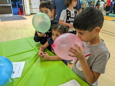 Greensboro Science Center family science night at Guilford Elementary School with children smelling balloons
