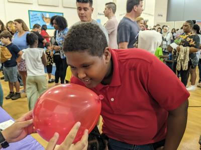 Greensboro Science Center family science night Smelly Balloons activity with a student smelling balloon