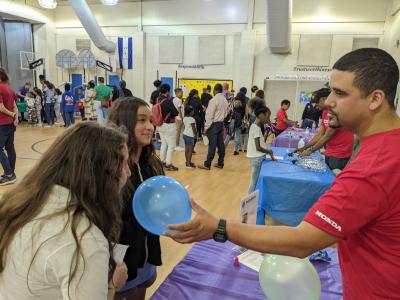 Greensboro Science Center family science night Smelly Balloons activity in school gymnasium