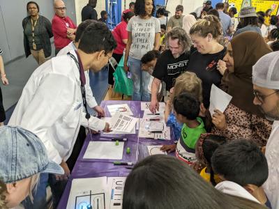 Greensboro Science Center family science night with families crowded around an hands-on activity table 