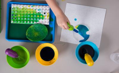 Young child using water dropper to mix colors in Early Explorations activity.