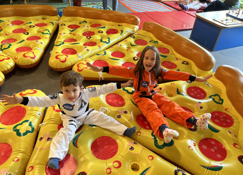 Space Weekend 2023 - Giant Inflatable Pizza with Kids Dressed as Astronauts Bouncing on Top
