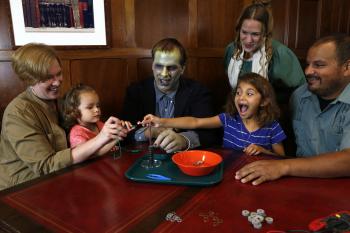Children with surprised faces and adults using the Frankenstein kit Battery Stack activity - adults dressed as Mary Shelley and the Monster