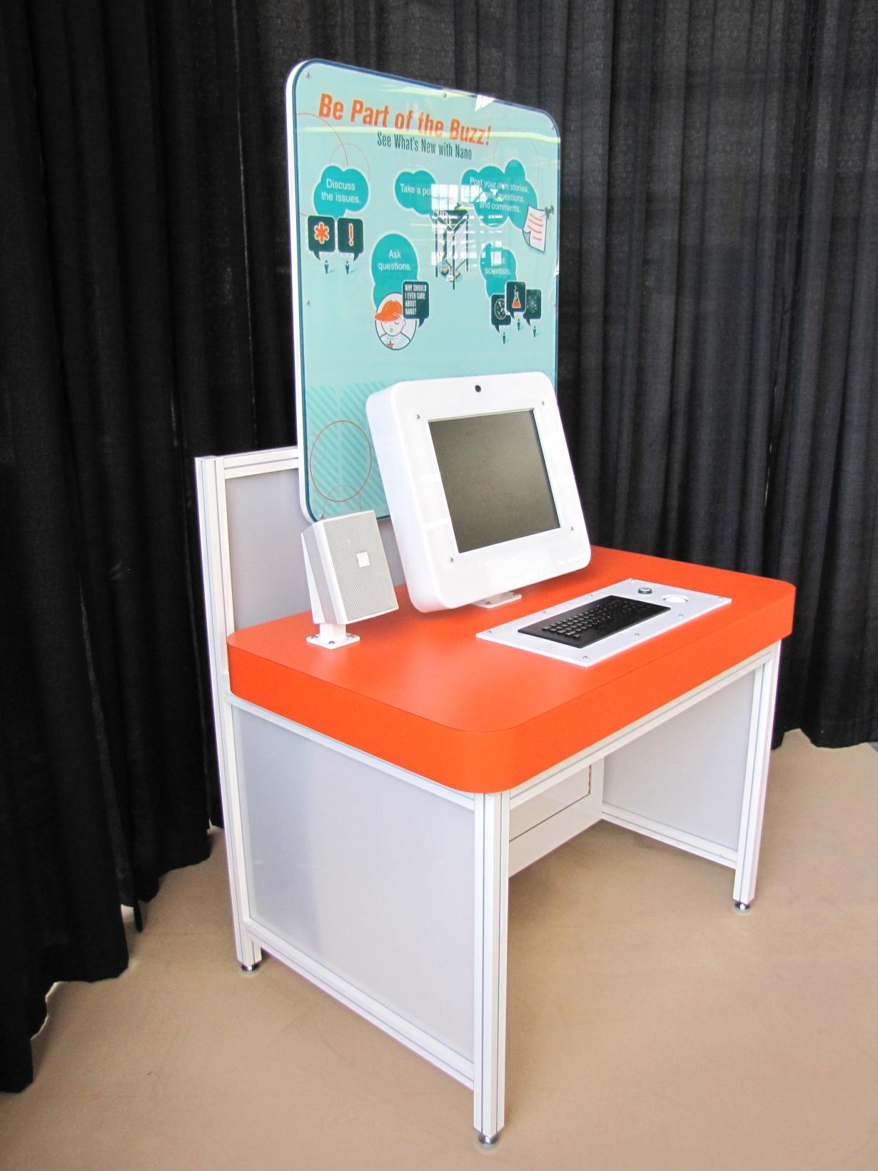Large blue and orange desk interactive exhibit with a computer that allows participants to find more information on nanoscience