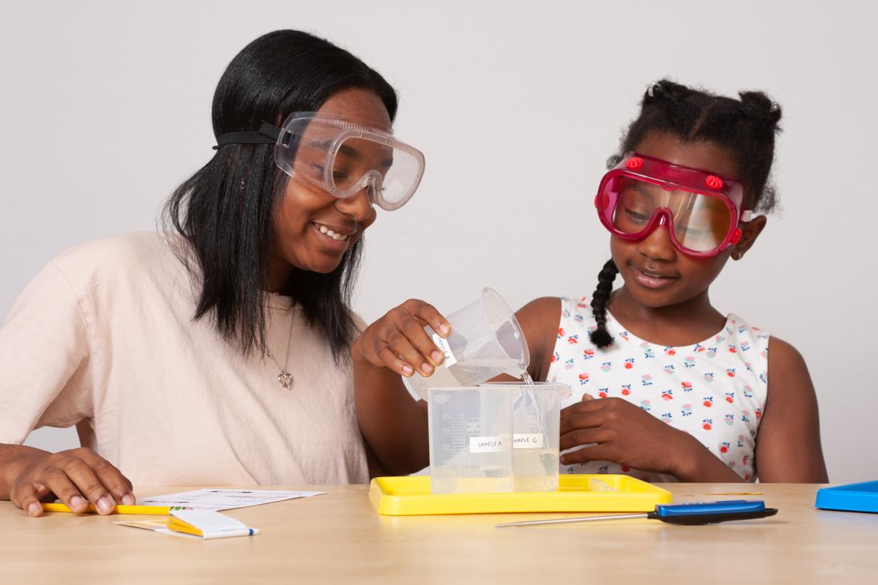 Two learners measure out water into a beaker