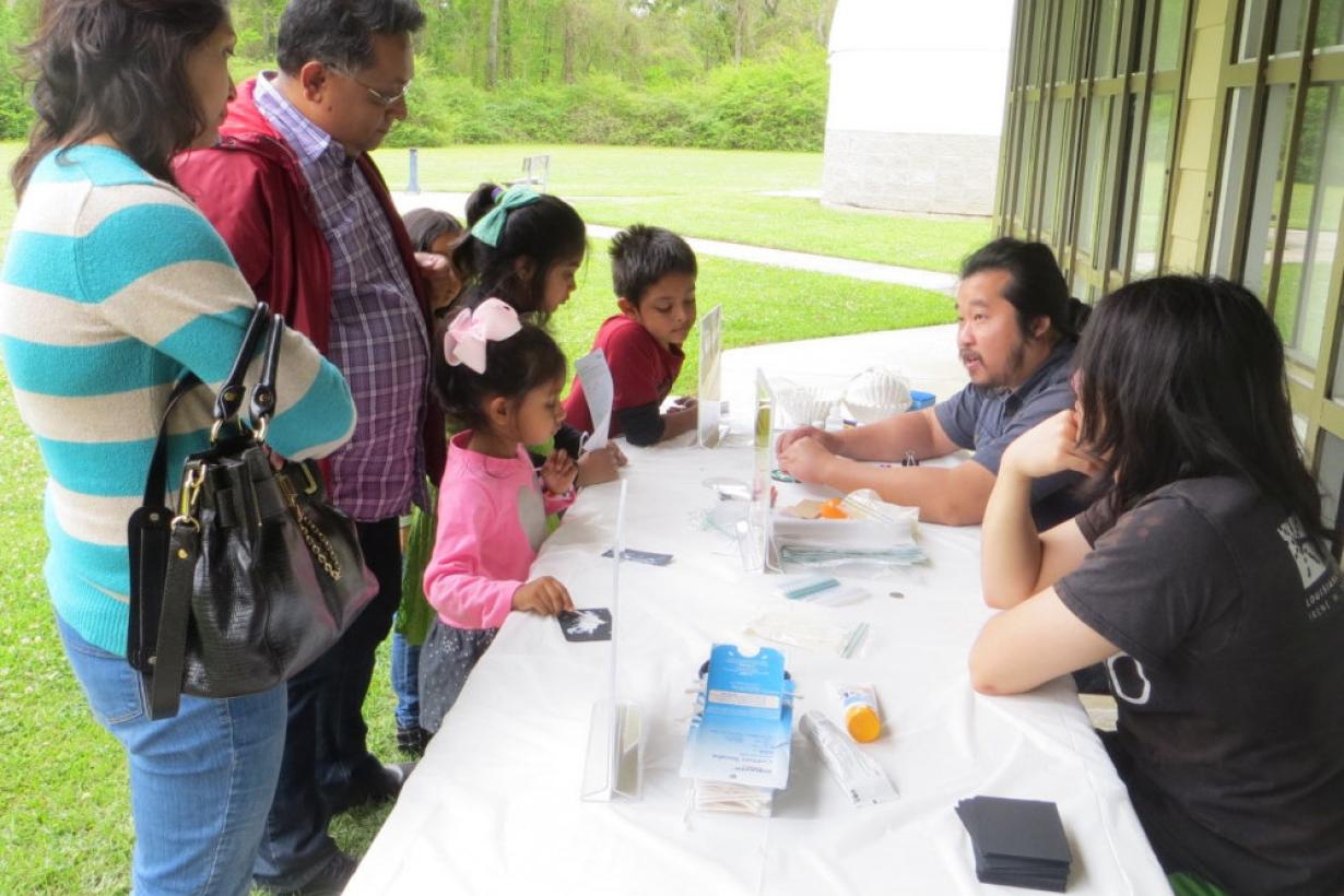 Children and adults using NanodDays Hands-on Sunblock  activity from a past NanoDays event at Highland Road Park Observatory in Baton Rouge, Louisiana 