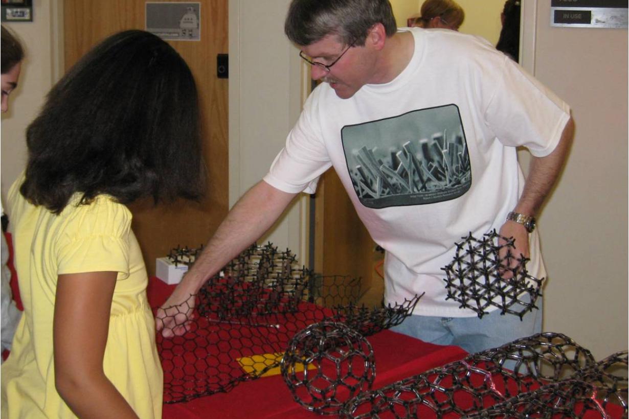 Faciltator showing physical models of carbon to a visitor at a NanoDays event