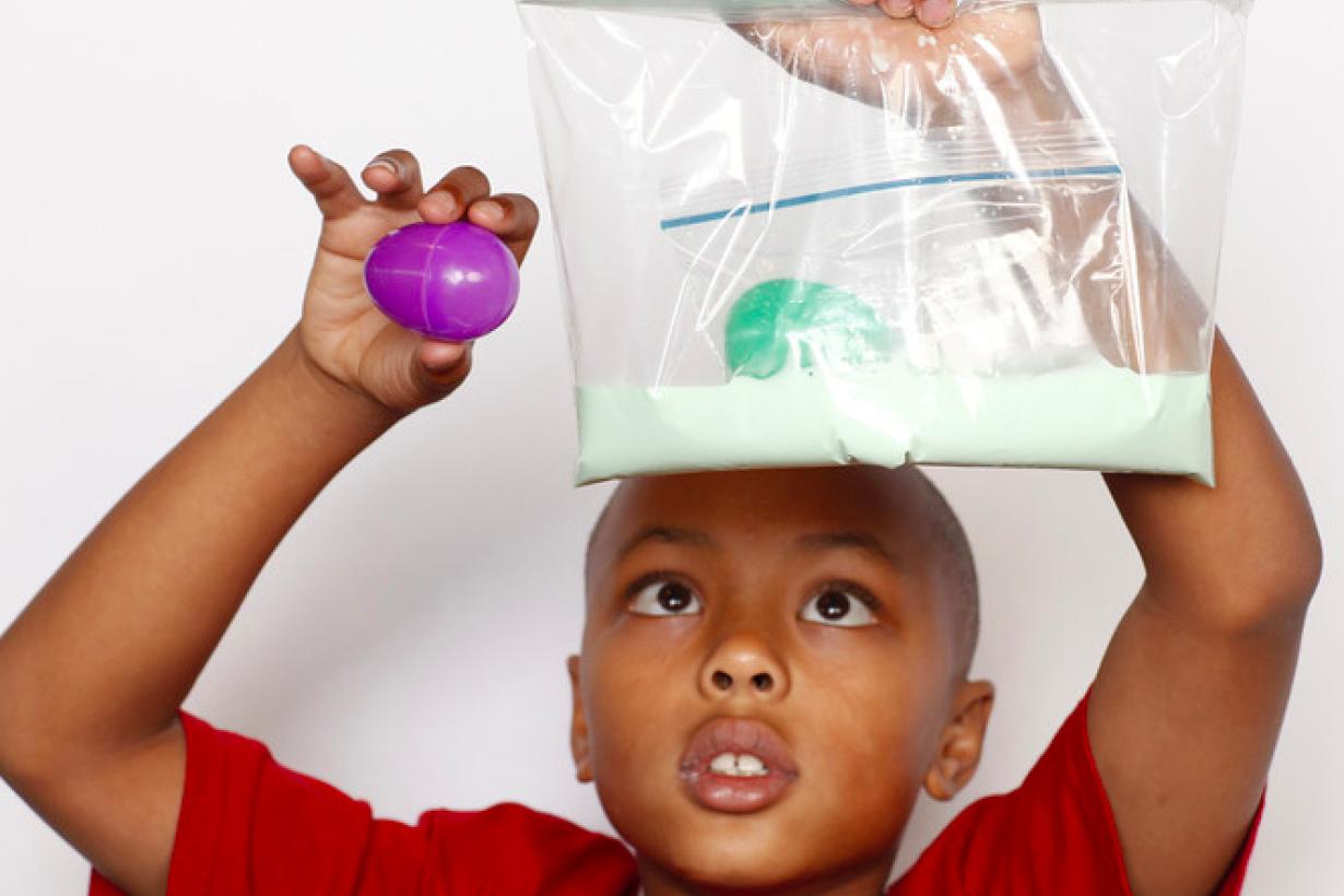 Boy holding a plastic bag of green oobleck with a plastic Easter egg