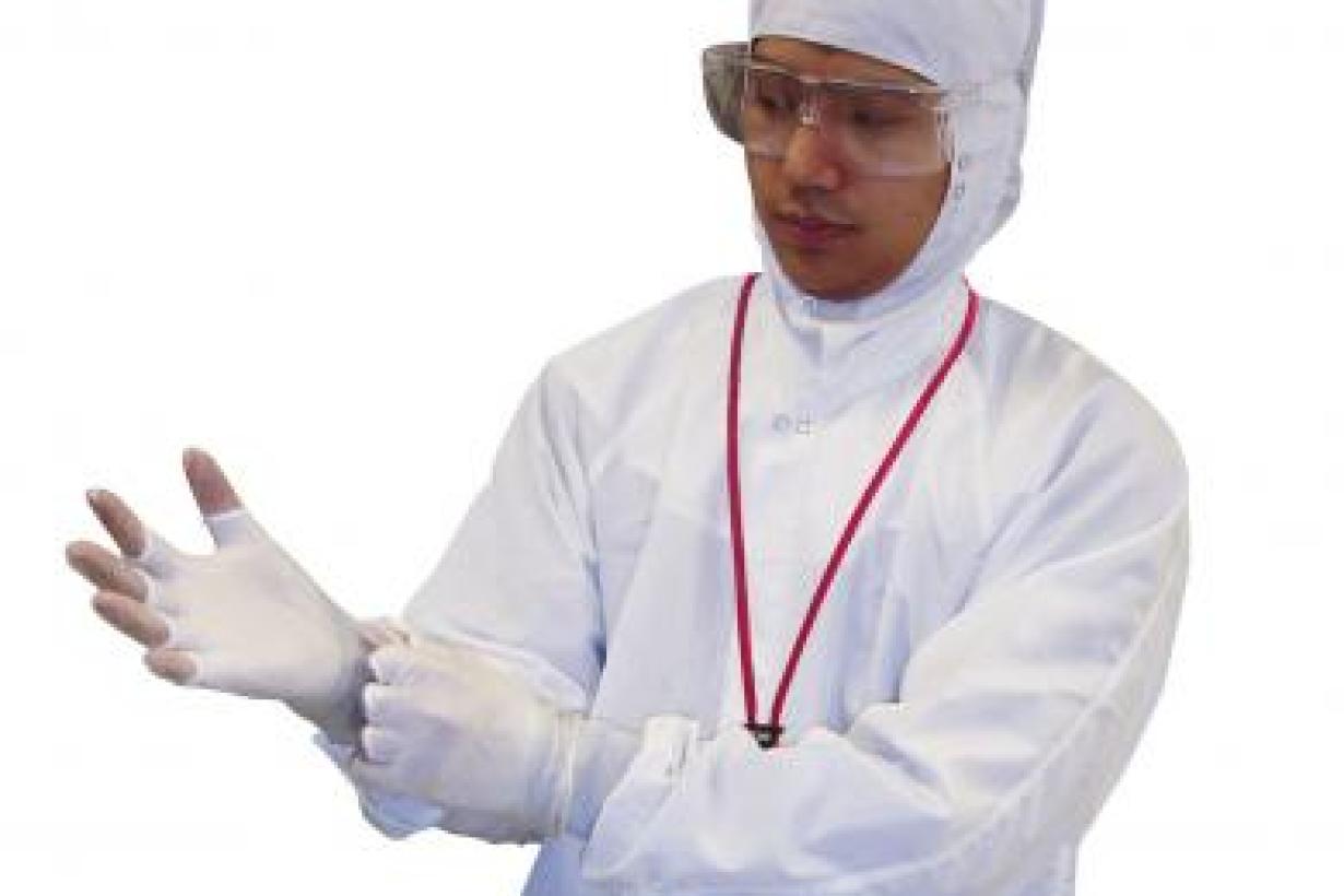 Nanoscientist dressing to go into a clean room with a white suit, gloves, and protective eyewear 