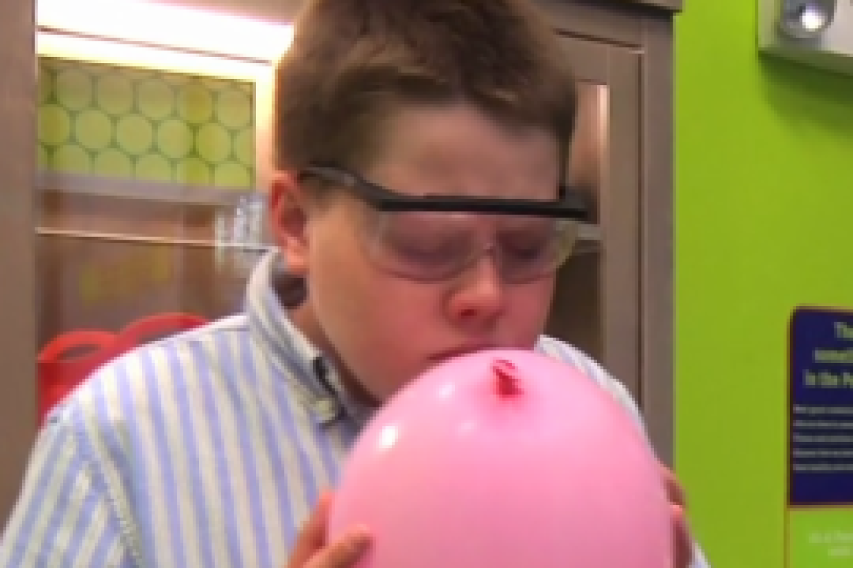Learner with safety goggles smelling a balloon with scent molecules 