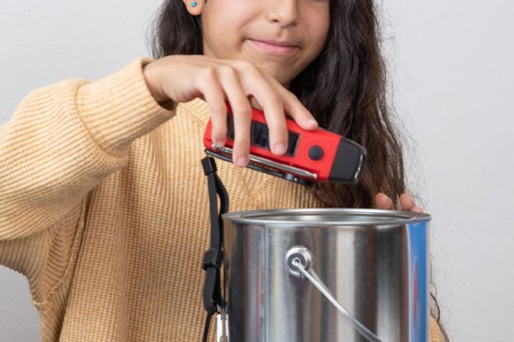 A child places a handheld radio into a metal paint can.