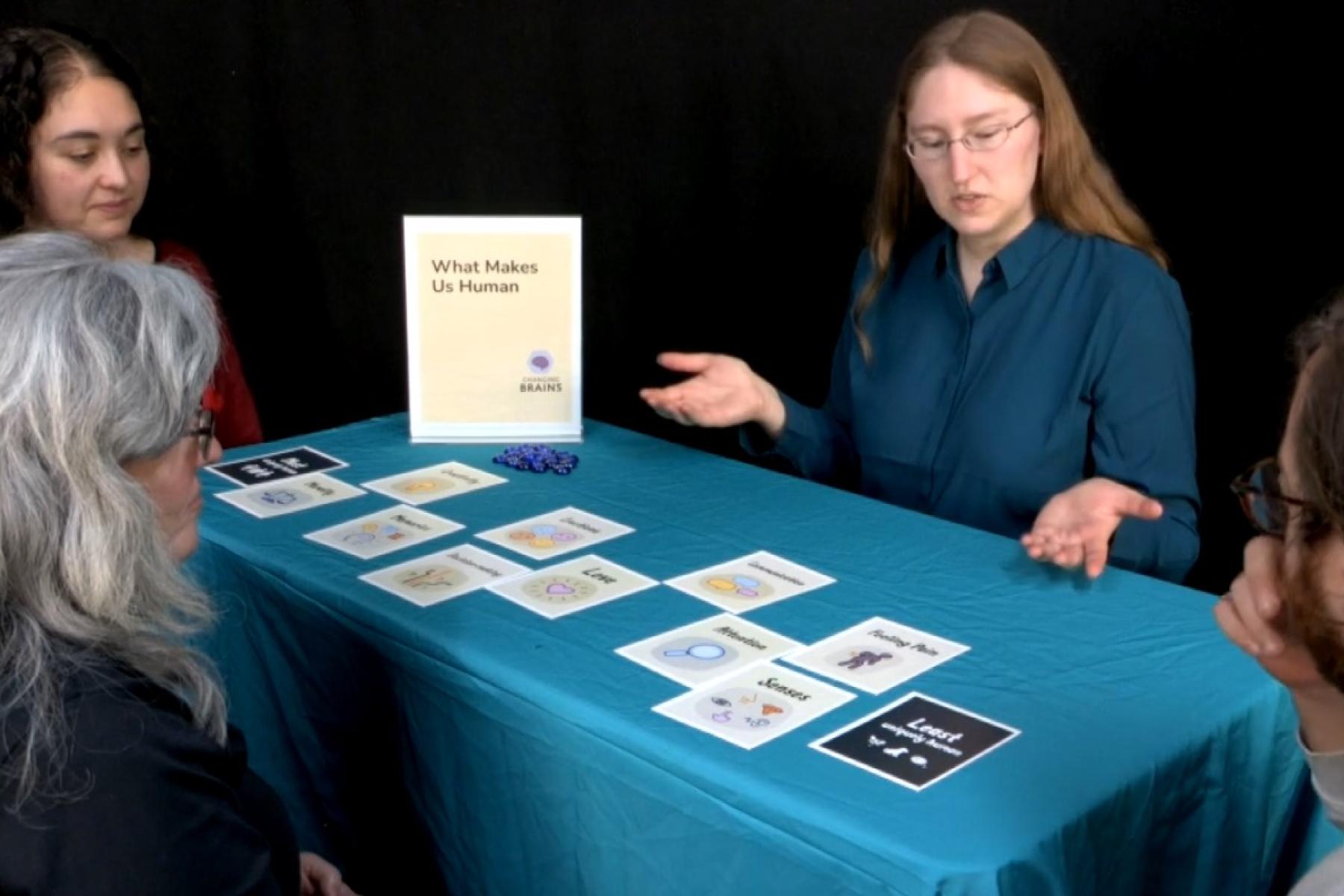 a facilitator gestures to cards on a table while three players look on