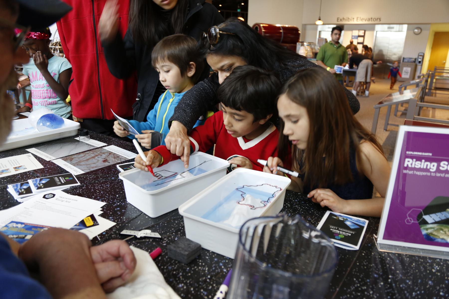 Children using Rising Seas activtiy at Science Museum of Minnesota event participating by drawing and looking at activity