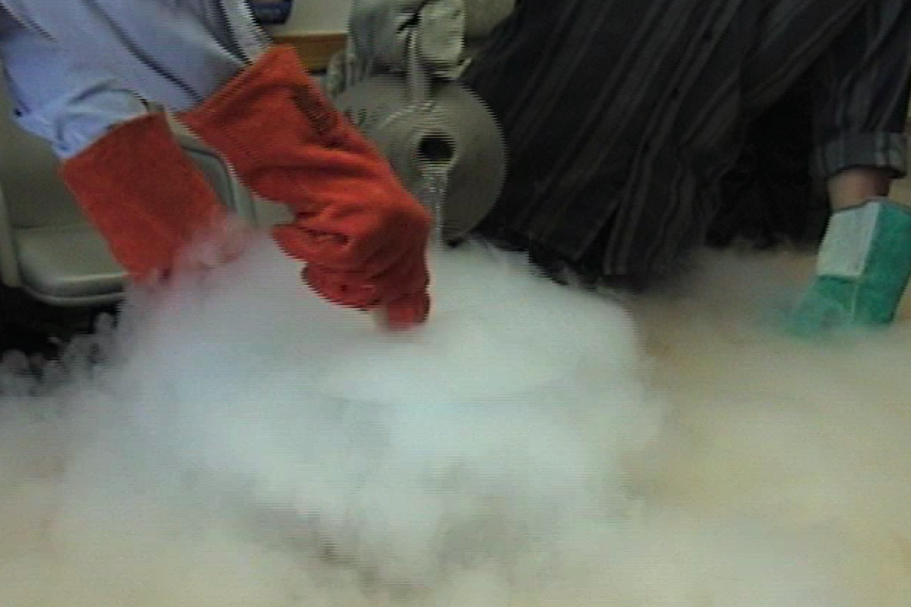 Person wearing red safety gloves liquid nitrogen being poured into a vat of cream