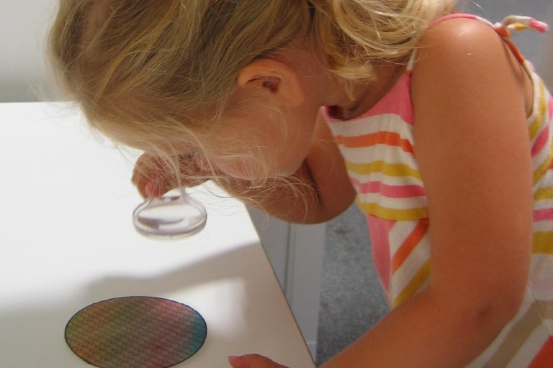 Little girl looking at a silicon wafer in the NanoLab exhibit
