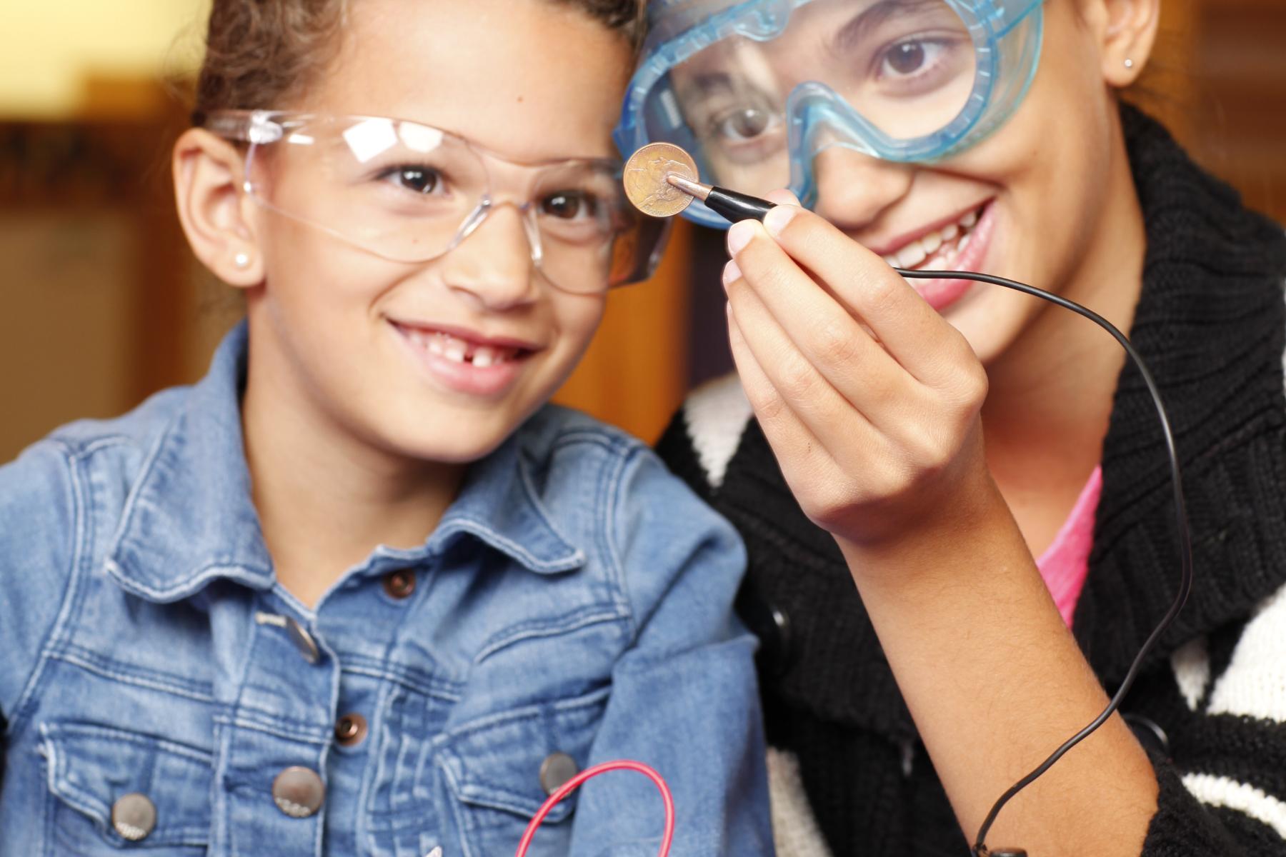 A girl and boy look at a penny that is being electro-plated with copper.