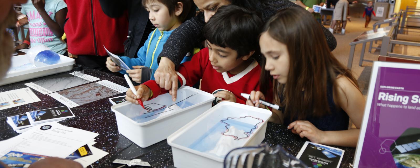 Children using Rising Seas activtiy at Science Museum of Minnesota event participating by drawing and looking at activity