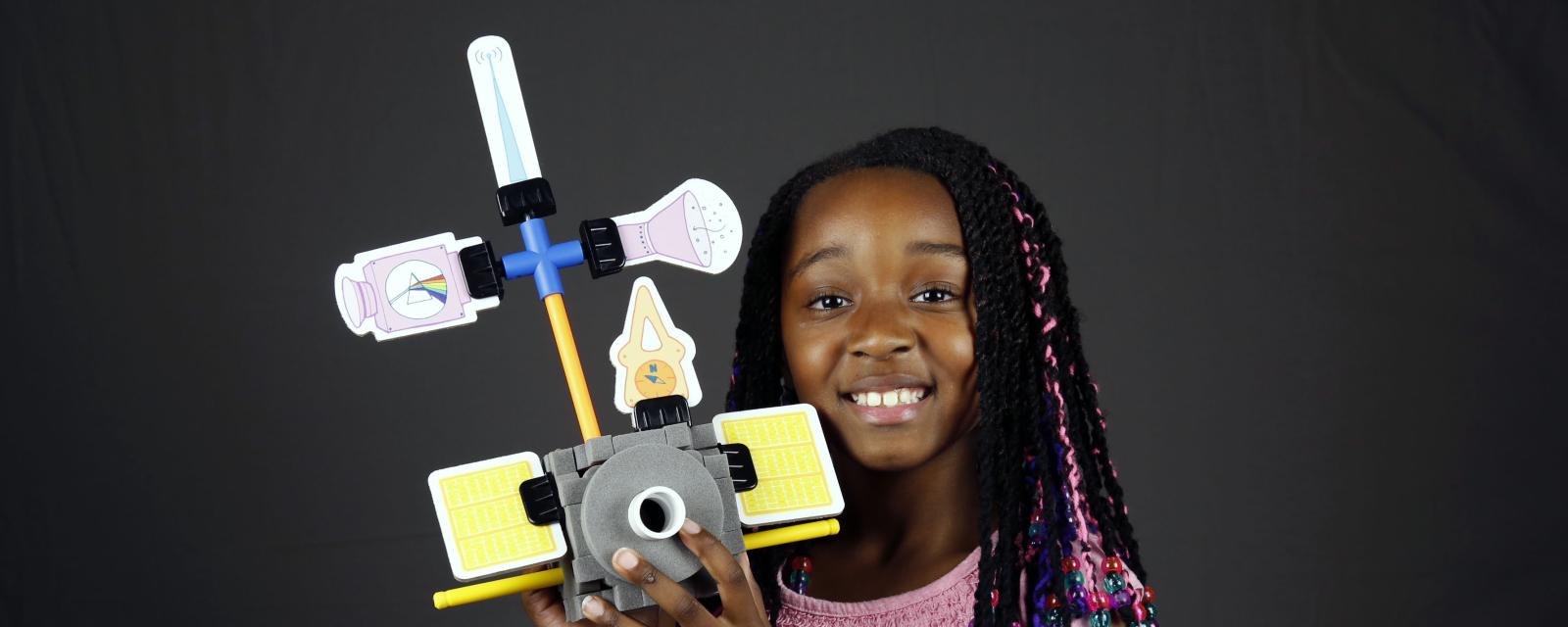 Girl holding a model of a spacecraft she built with Design Build Test engineering activity