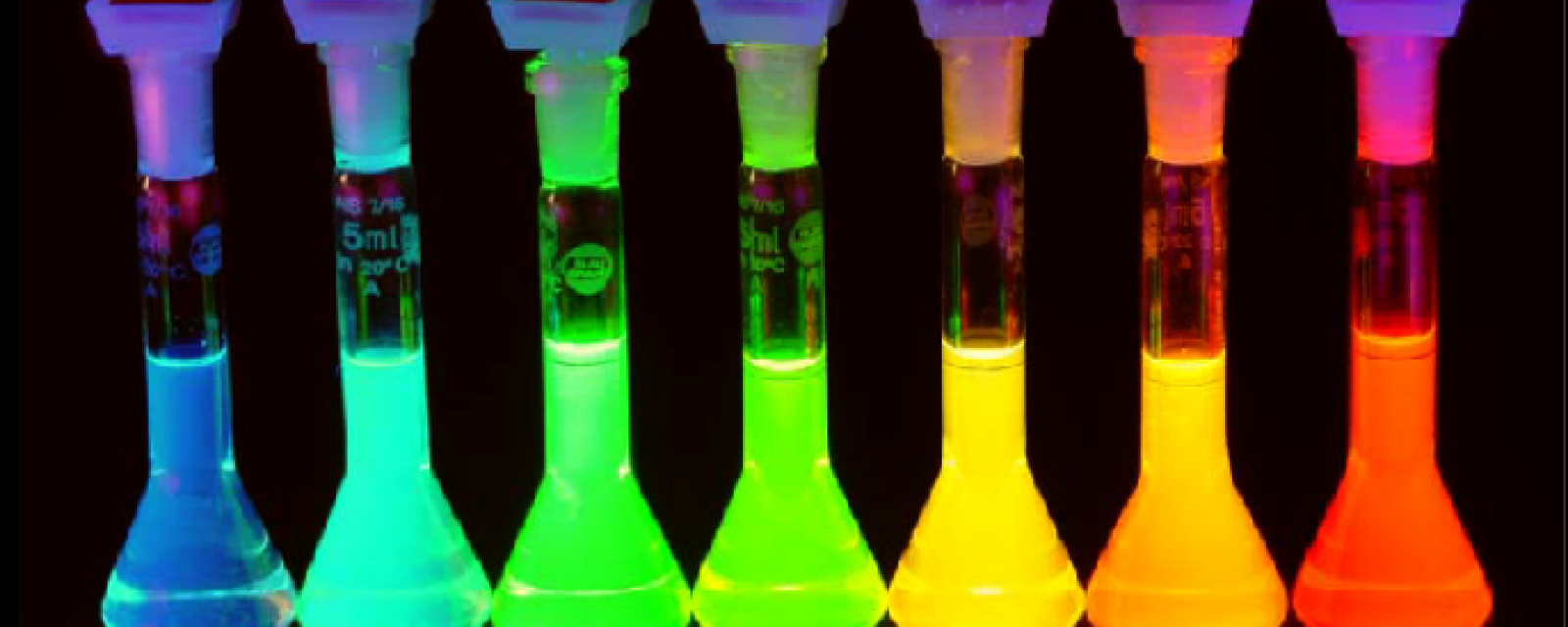 7 vials filled with quantum dots which are lit up and emit colored light